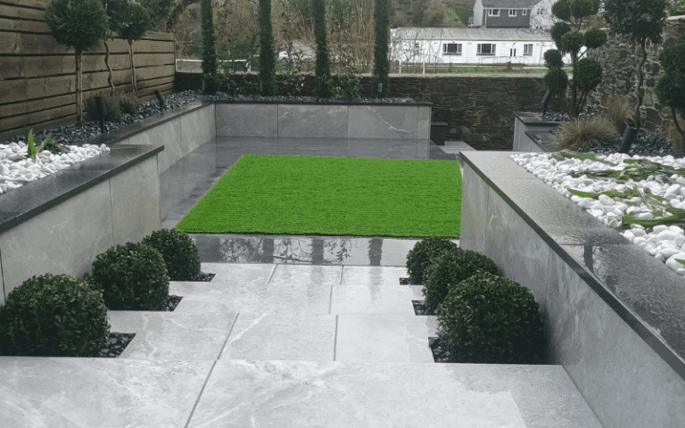garden paving and steps down to a square of astroturf.